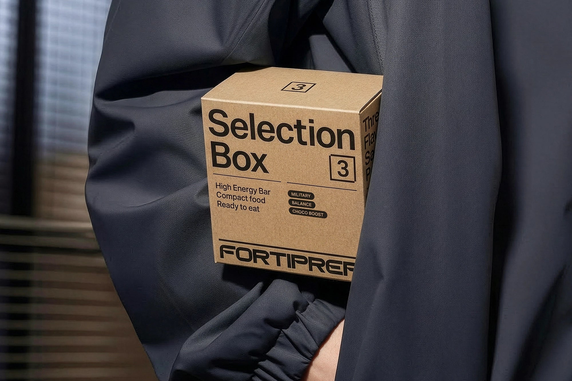 3 Selection Box feliratú kartondoboz kabát alá fogva, vakuval megvilágított részletekkel és kontrasztos textúrákkal.
